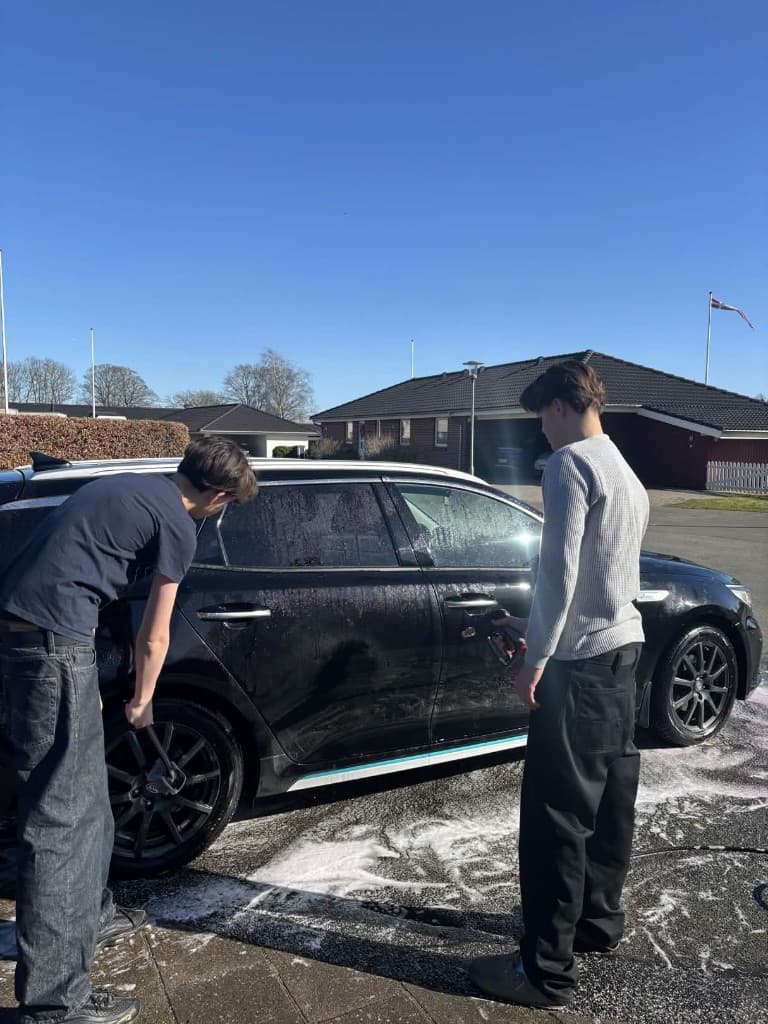 Victor og Oscar vasker en sort bil i solskinsvejr